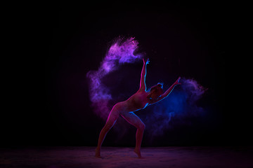 Graceful girl dancing in color powder cloud