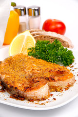 salmon with spicy sauce on a white plate with greens