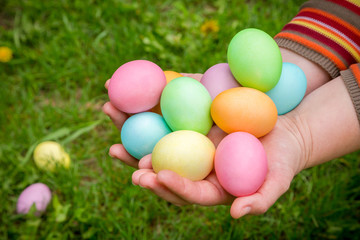 Fototapeta na wymiar colorful easter eggs in hands on green lawn