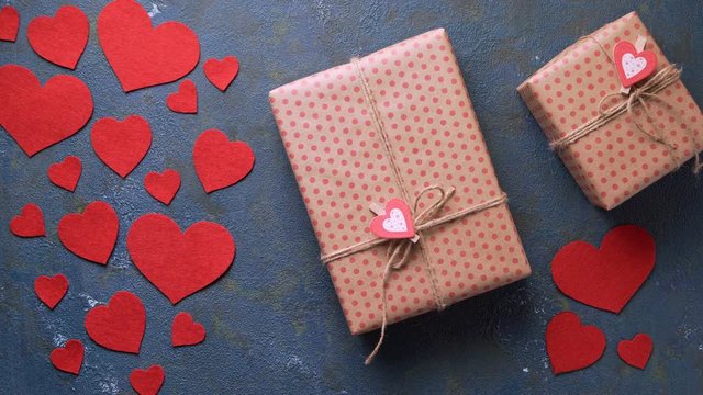Valentine's Day holiday gift box concept of romantic love surprise appears in frame on vintage blue table with red hearts decorations flat lay. Blank space for design