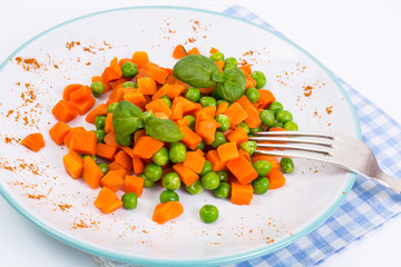 Mix orange carrots and green peas with olive oil and curry