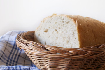 The bread is placed on a pattern die of the tablecloth. White background. In a wooden wicker basket.