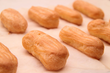 Long rows Eclair shells. Eclairs candy paper. The process of making cakes.
