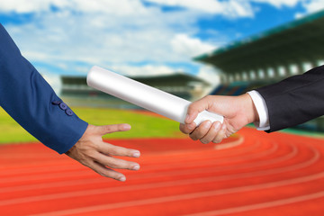 Cropped hand of businessman passing relay baton to colleague