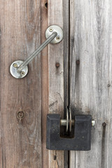 Closed and locked wooden old door with handle, padlock and nail heades