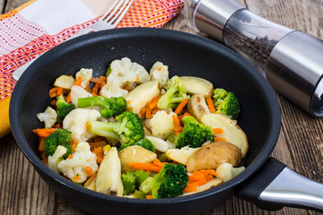 Mixed vegetables frying pan on background of old boards