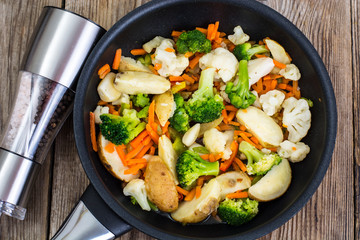 Mixed vegetables frying pan on background of old boards