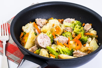 Vegetable stew with sausage grilled slices in a frying pan on a 