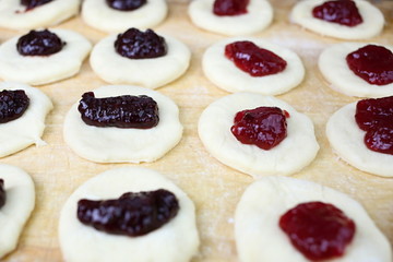 Raw sweet yeast dough on a wooden table, filling buns jam. Preparation for baking. The concept of chefs and baking.