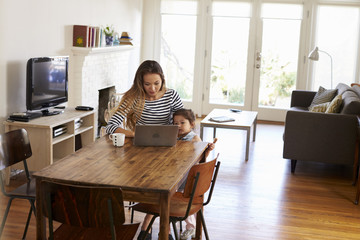 Mother And Daughter Using Laptop At Home Together