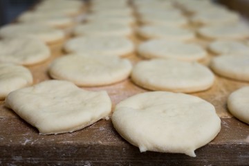 Fototapeta na wymiar Raw sweet yeast dough on a wooden table. Preparation for baking. The concept of chefs and baking.