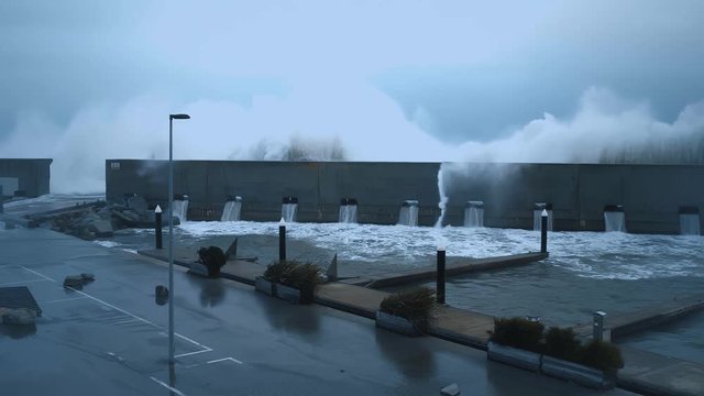 View on strong storm in sea from marina on the shore, huge powerful waves smash coast guard wall
