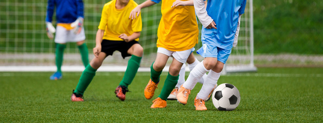 Obraz premium Football Soccer Match for Children. Kids Playing Soccer Game Tournament. Boys Running and Kicking Football. Youth Soccer Goalkeeper in the Background
