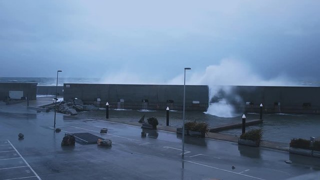 Close view on very strong and powerful storm at mediterranean cost at winter, huge waves smash on barrier that protecting small marina, ponds are emty of boats