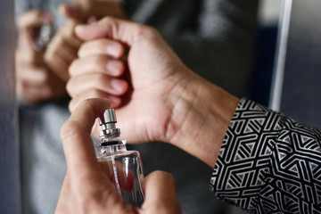 young man spraying perfume on his wrists