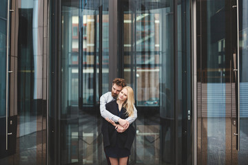 Love Story. The guy hugs the girl. Glass building.