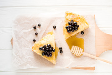 Homemade pancakes with berries and honey on a white background