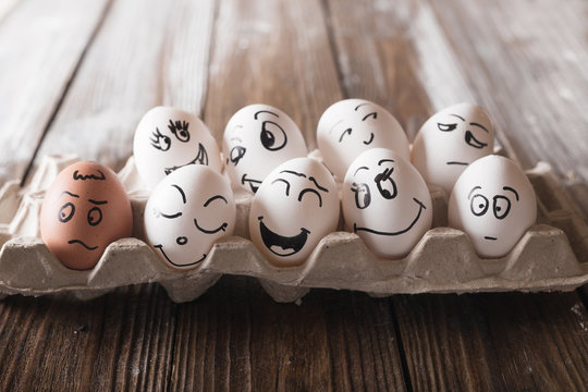 Eggs with funny faces in the package on a wooden background. Easter Concept Photo. Eggs. Faces on the eggs Eggs