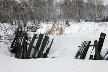 Snow-covered old village rotten fence 30106