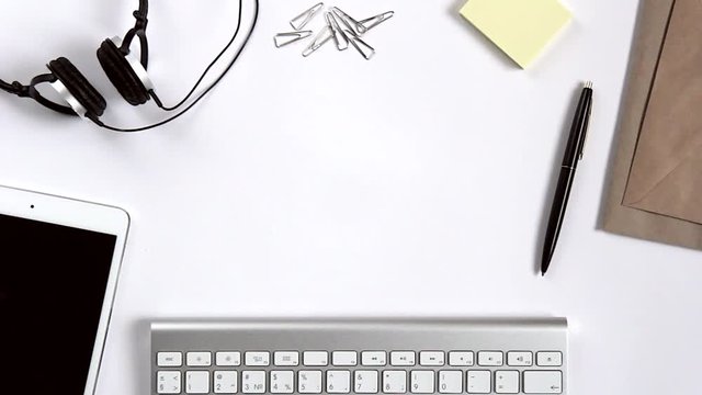 Keyboard, mouse, tablet, headphones, stationery, notebook on white office desk