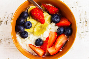 Low fat breakfast.Cottage cheese with blueberries, banana, almonds and strawberries on white background.