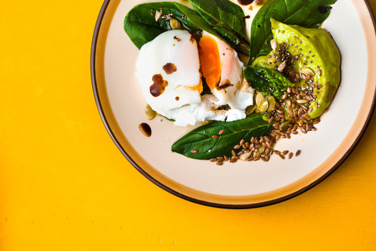 Poached Egg With Avocado Cream And Spinach On The Yellow Background Top View