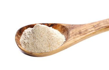 pile whole grain barley flour and wooden spoon isolated on white background