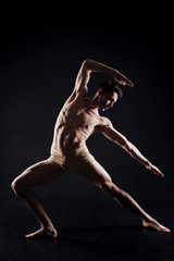 Fototapeta na wymiar Handsome man practicing yoga in the dark lighted studio