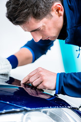 Hard-working man polishing car with white microfiber mitt