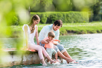 Glückliche Familie am See sitzt auf Steg