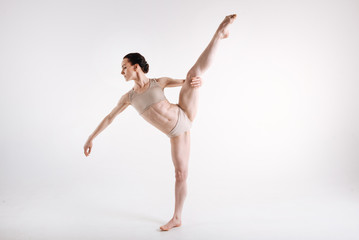 Elegant young gymnast stretching against white background