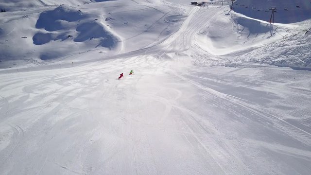 4k aerial footage, drone following two skiers on ski slope in skiing region
