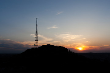 Beautiful sunset upon Lviv city. Telecommunication tower on the mountain High Castle.