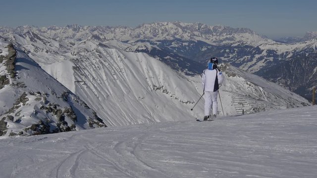 Skier in white on a background of snowy mountains