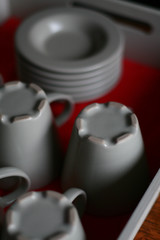 Grey coffee cups and saucers on a white tray with a red bottom