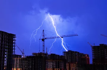Acrylic prints Storm Lightning storm crane weather industrial city building construction night flash
