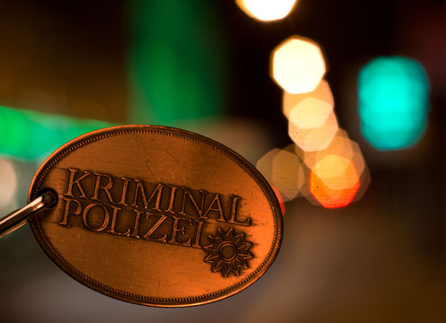 Polizeimarke Marke der Kriminalpolizei Deutschland mit den Lichtern der Stadt im Hintergrund