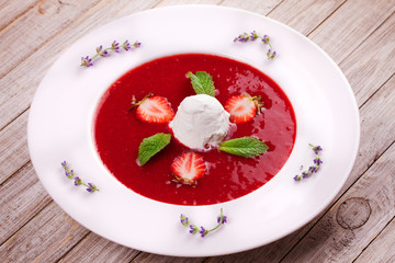 Strawberry soup with ice cream and mint. Pureed strawberries garnished with mint leaves topped with vanilla ice cream. Blended berries. Berry dessert