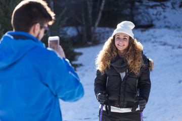 Happy young couple taking photos over winter background.