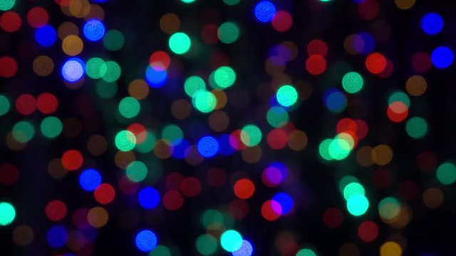 Abstract bokeh holiday greeting background. Decoration of blinking garlands. Christmas and new year lights twinkling. Celebration spirit in merry flashing colorful bubbles on night backdrop in 4k clip