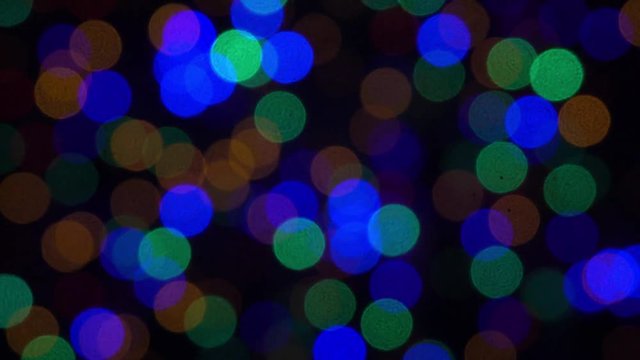 Abstract bokeh holiday background. Decoration of blinking garlands. Christmas and new year lights twinkling. Celebration spirit in merry flashing colorful bubbles on dark night backdrop.
