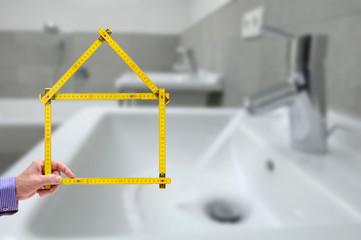 Meterstab symbolisch als Modellhaus im Badezimmer