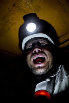 miner helmet shouts of fear/Portrait of angry coal miner shouting against a dark background in Russia