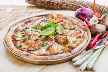 Delicious Seafood Pizza on a wooden table with ingredients aroun