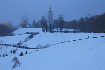 Frosty winter morning in the park. National Museum "Memorial to Holodomor victims" and top of Great Lavra Bell Tower is disappearing in the fog. Kiev. Ukraine