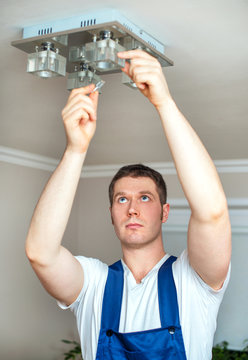 Male electrician changing lamp bulb.