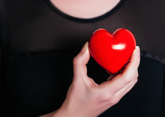 People, relationship and love concept - close up of womans cupped hands showing red heart