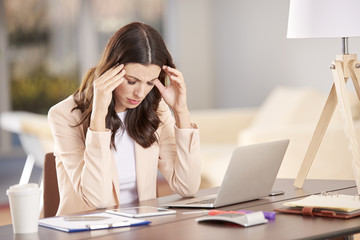 Stressed woman in the office. Shot of a distracted young businesswoman sitting in front of laptop...