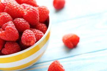 Red raspberries in bowl on a blue wooden table