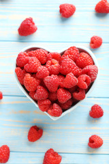 Red raspberries in bowl on a blue wooden table
